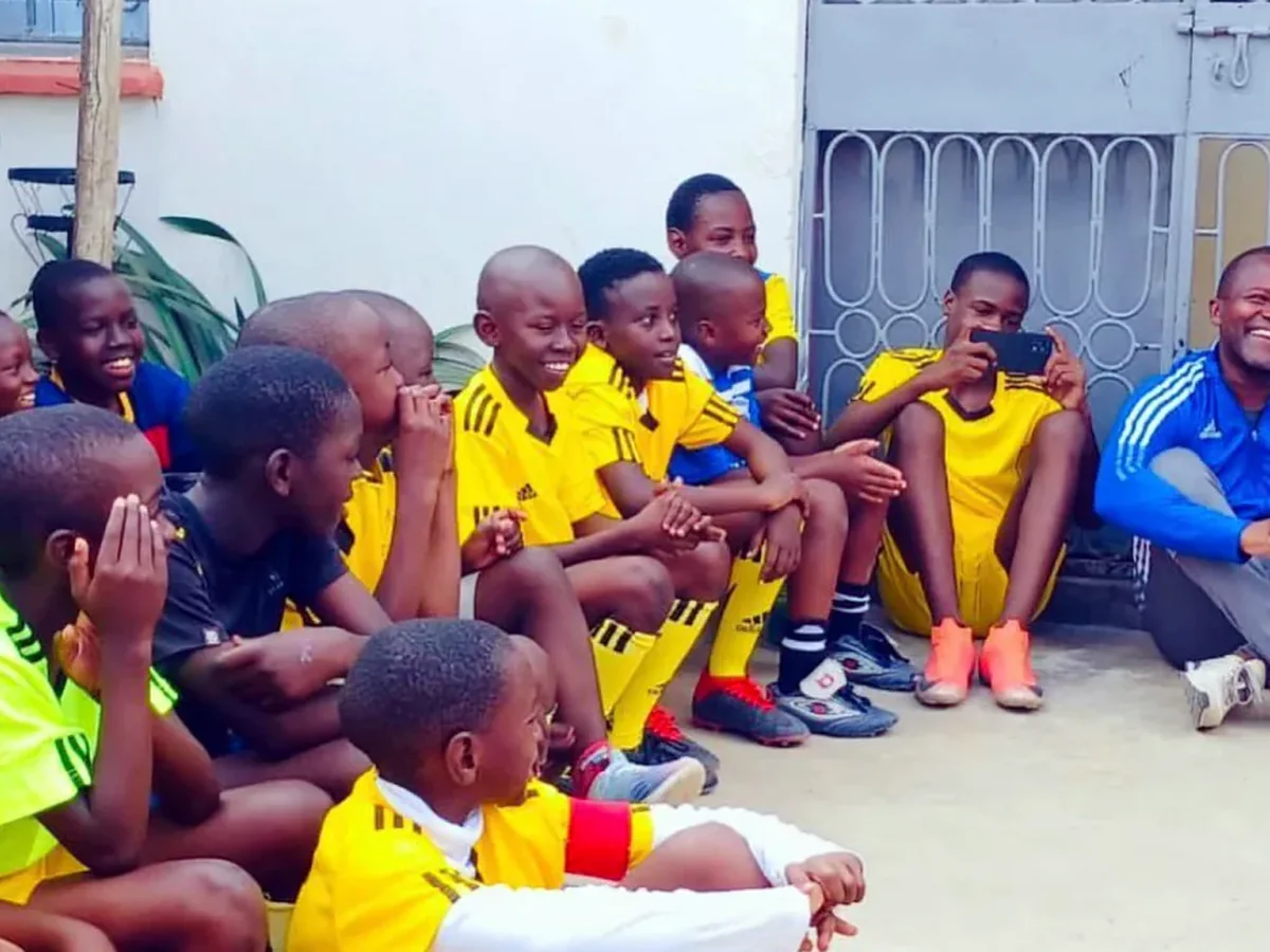 Youth players in yellow kits laughing together after a community football session