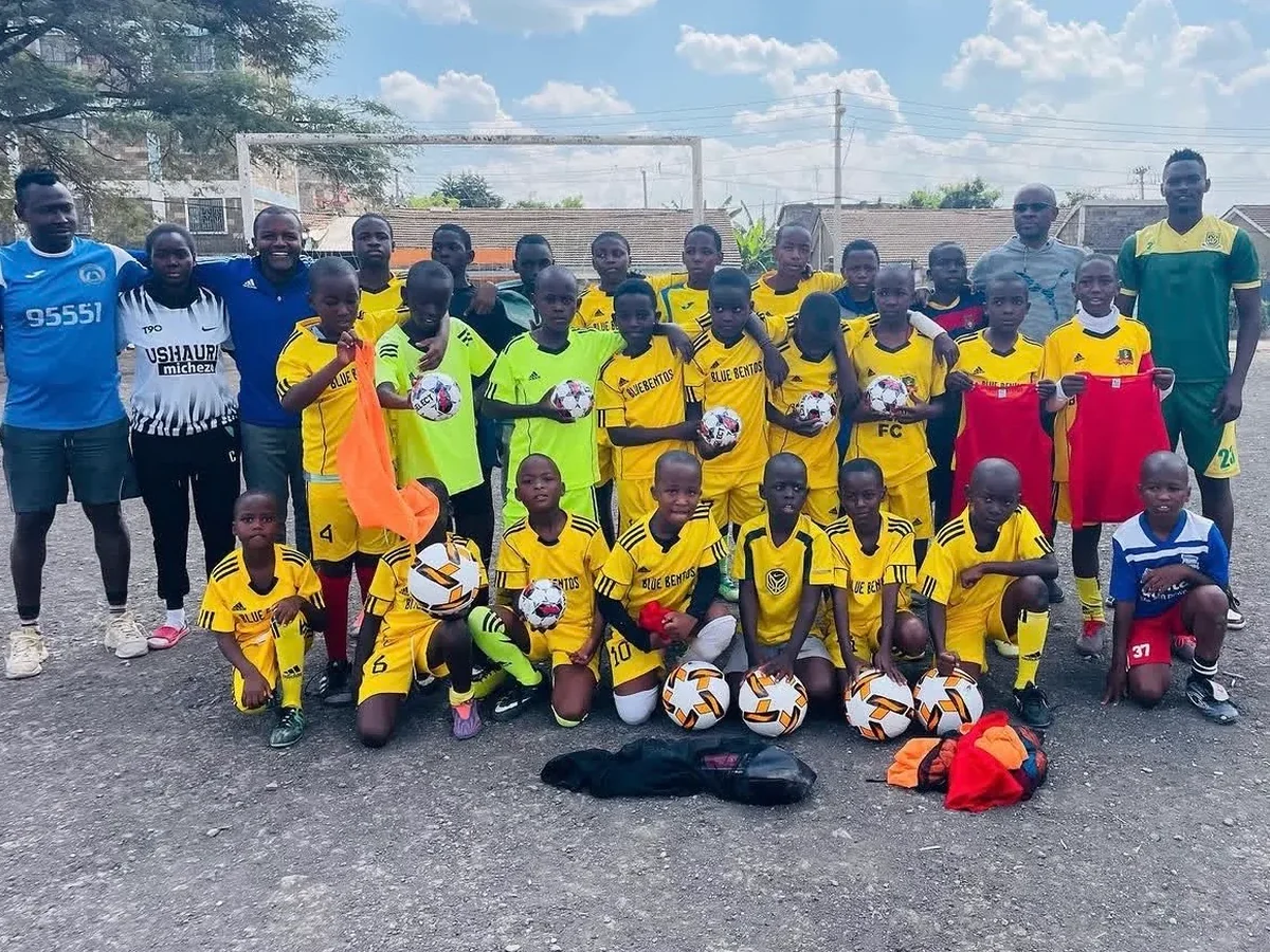 Blue Bentos FC youth team proudly holding footballs after a gear donation